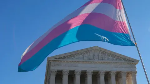 Getty Images A blue pink and white trans gender flag flies over the US Supreme Court with a blue sky in the background