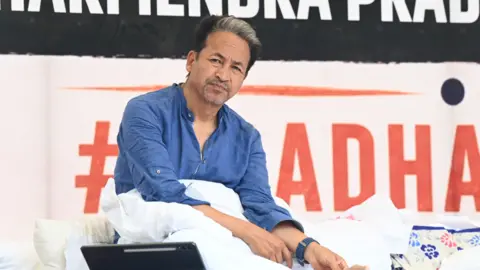Hindustan Times via Getty Images Activist Sonam Wangchuk - wearing a blue shirt - looks sideways as he sits on a hunger strike in Delhi 