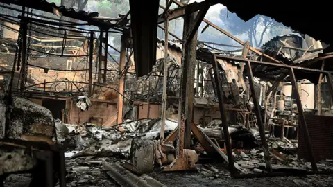 Getty Images Charred remains of a home burned in the wildfires in the Madrid community. Burned out chairs and beds and fabric litter the floor