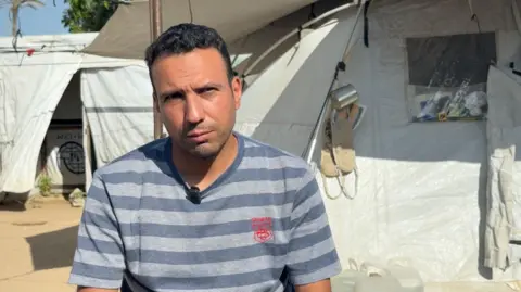 BBC Saber Abu al-Kas sits outside a tent in Gaza