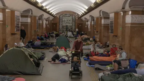 AFP via Getty Images Tents, sleeping bags and roll-up mattresses used by people camping out in an underground metro station in central Kyiv.