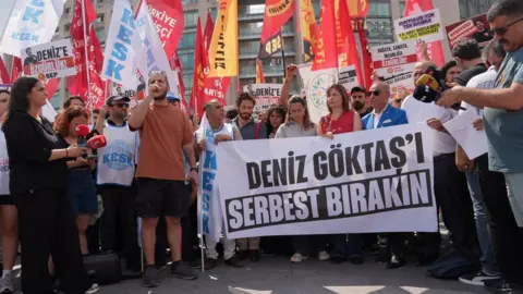 Aynur Tekin/BBC Men and women gather with placards in Turkish