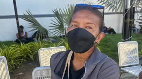 BBC Mundo Liliana González, a 60-year-old woman sitting in a chair and wearing a black face mask.