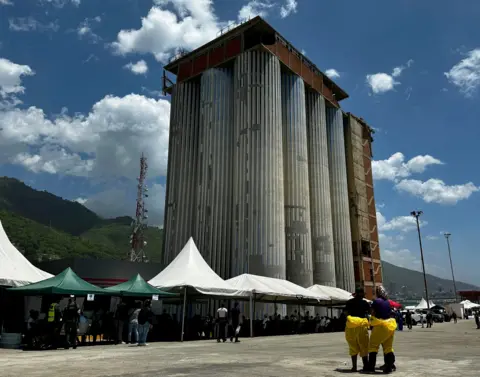 BBC Mundo Los Silos facilities, dominated by a large, 36-meter-tall tower. White tents and people in hasmat suits stand in front. 