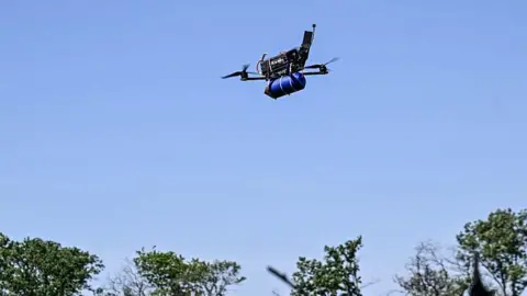 Ukrinform/NurPhoto via Getty Images A remotely controlled FPV drone, equipped with ammunition, is seen in the sky during a combat mission of a Ukrainian drone unit in 2025