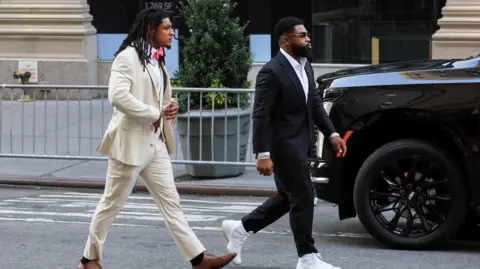 Reuters NFL athlete Isiah Pacheco arrives at Madison Square Garden wearing a cream suit and tan shoes.
