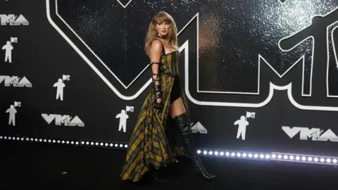 Getty Images  Taylor Swift wearing a yellow and green tartan dress at the MTV 2024 Video Music Awards 