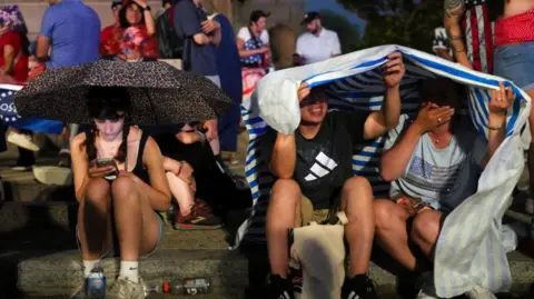 Reuters People take cover from the rain amid stormy weather ahead of a Fourth of July rally featuring U.S. President Donald Trump to mark the 250th anniversary of U.S. independence, in Washington, D.C., U.S., July 4, 2026. 