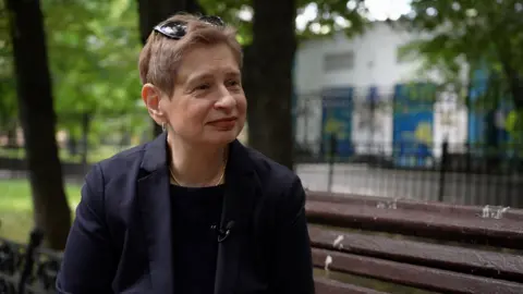 Nina Khrushcheva sits on a bench in Moscow as she speaks with the BBC