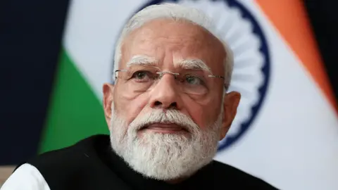 Reuters India Prime Minister Narendra Modi sitting in front of an India flag