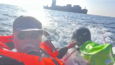 Dong Guangping Dong Guangping takes a photo of himself in an orange life jacket while navigating a boat at sea