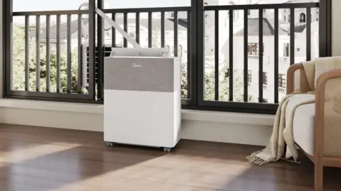 Midea A Midea PortaSplit by the window of an apartment, with a tube connecting the indoor and outdoor units