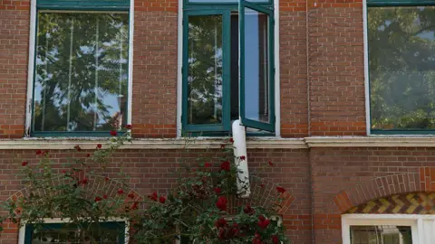 Getty Images A portable air-conditioning unit's exhaust pipe hangs out of a window