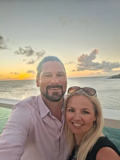Sarah Reeve Man and woman smiling in front of the sea and sunset 