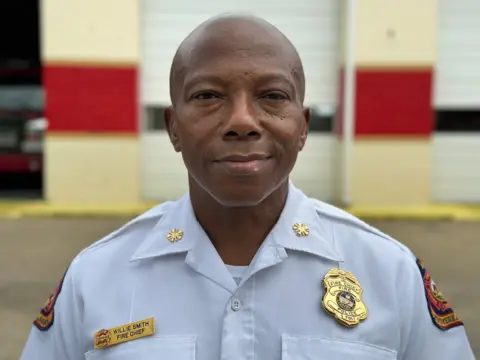 Brandon Drenon/BBC Tuskegee Fire Department Chief Willie Smith poses in front of the fire department for a portrait 