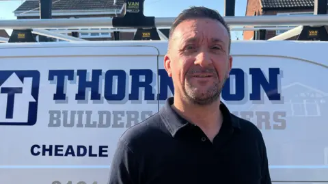 Richard standing in front of a white van smiling.