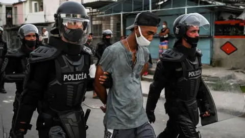 AFP via Getty Images A man is arrested during a demonstration against the government of President Miguel Diaz-Canel in Arroyo Naranjo Municipality, Havana on July 12, 2021. 