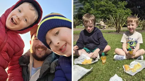Kieron Fisher A composite picture: On the left side, six-year-old twins Kit and Ollie lean into the camera with their dad in between them - they are wearing jackets and hats, and there's clear blue sky behind them. On the right side, the boys sit cross-legged on some grass while picnicking, eating a sausage roll and some crisps in broad sunshine