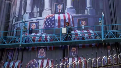 EPA An Iranian worker adjusts an anti-US billboard featuring pictures of US President Donald Trump and his family on top of US flag-draped coffins, in Tehran, Iran, on 16 July 2026
