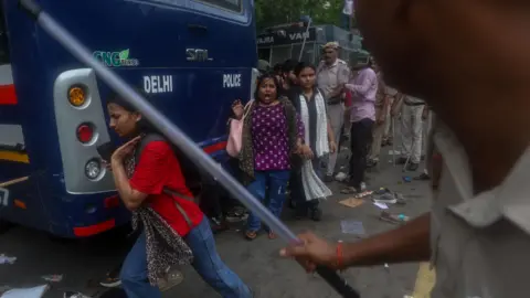 EPA/Shutterstock Indian security personnel use lathi charge as they attempt to stop Cockroach Janta Party's(CJP) supporters during a march toward Parliament in New Delhi, India, 20 July 2026. Demonstrators from the youth-led political movement gathered to demand the resignation of the Union Education Minister over examination paper leak irregularities, following the court-ordered medical evacuation of activist Sonam Wangchuk, according to statements from the Delhi Police.
