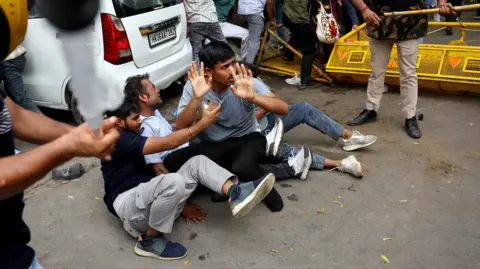 Reuters Security force personnel wield batons against demonstrators at a protest site during a planned march by supporters of India's Cockroach Janta Party towards parliament on the opening day of its monsoon session, demanding the resignation of Education Minister Dharmendra Pradhan over exam paper leaks near Jantar Mantar, New Delhi, India, July 20, 2026.