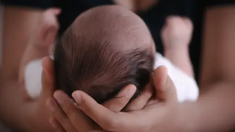 Getty Images Baby cradled in the arms of a mother.