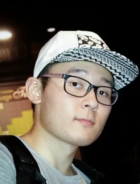 Family handout A young Korean man wearing a white and black cap and glasses looks into the camera