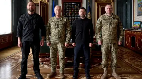 Ukrainian Presidential Press Service/Handout Right to left: Newly appointed Commander-in-Chief of the Ukrainian Armed Forces Major General Mykhailo Drapatyi, Ukraine's President Volodymyr Zelenskiy, Drapatyi's predecessor General Oleksandr Syrskyi, and Acting Defence Minister Yevhenii Khmara pose for a picture after a meeting,