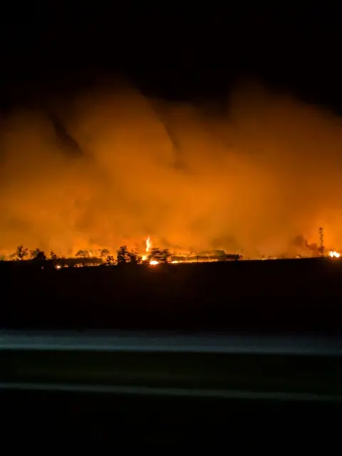 David Morton Flames are seeen next to the road illuminating the sky orange.