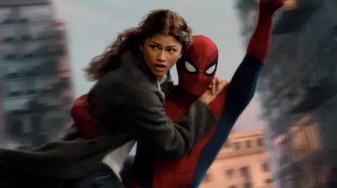 Sony Pictures/Marvel Zendaya as MJ holding on to Spider-Man, played by her husband Tom Holland, as they swing through the air