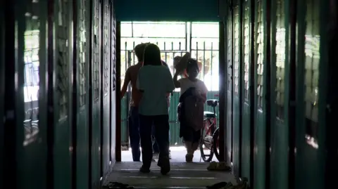 BBC/ Lulu Luo Burmese people stand at the end of a narrow corridor inside a cluster of safe houses in Thailand's Mae Sot town that borders Myanmar