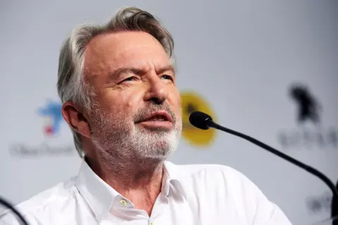 Getty Images A head and shoulders crop of Neill looking away from camera while speaking into a microphone against a bokeh background, in Spain in 2019.