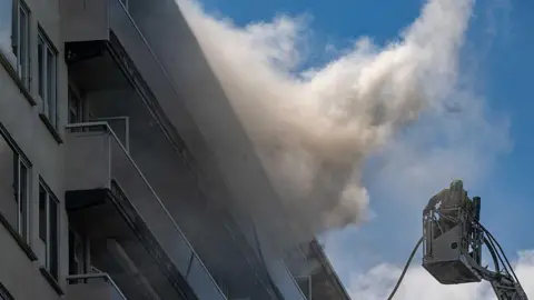 BELGA MAG/Belga/AFP Firefighters pictured at the scene of a fire in an apartment building in the August Vermeylenlaan street in Antwerp