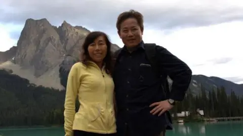 Reuters Chen Youlin (right) and his wife Rong Yufang pose for a photograph with the mountains and a lake in the background