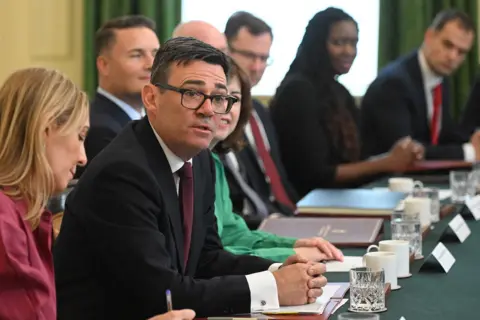 Pool via AFP Burham looks up and towards the camera while sitting at a desk surrounded by cabinet members during a cabinet meeting in Downing Street on 21 July.