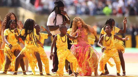Getty Images Shakira and Burna Boy perform with Ghetto Kids dancers dressed in yellow during World Cup 2026 final half-time show between Spain and Argentina on 19 July 2026 in New Jersey.