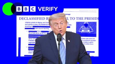 Getty Images President Trump speaking in front of a microphone with a graphic showing a declassified document behind him.