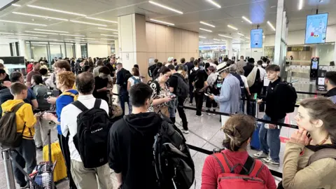 Getty Images Passengers wait in long queues at passport control in the departures terminal of Brussels Airport in Brussels, Belgium, on June 29, 2026.