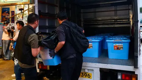 AFP via Getty Images Police officers load confiscated items into the back of a van