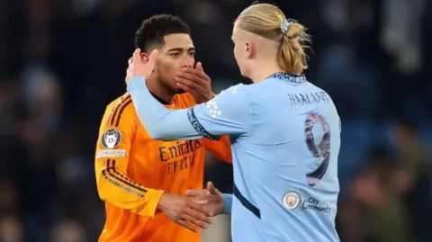 Carl Recine/Getty Images Jude Bellingham covers his mouth talking to Erling Haaland who is about to hug him