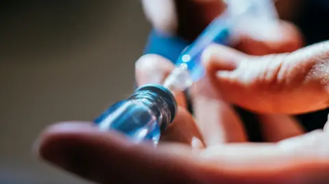 Getty Images A close up of a person's hands as they prepare an injection