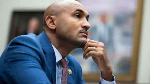 Getty Images Shomari Figures rests his chin on his hand, while wearing a blue suit