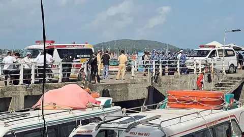 AFP via Getty Images Ambulances line up on a pier to help victims after a tourist vessel capsized off Phu Quoc island in southern Vietnam. Photo: 11 July 2026