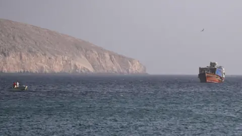 Reuters A large and small vessel are seen in the water, with land in the background