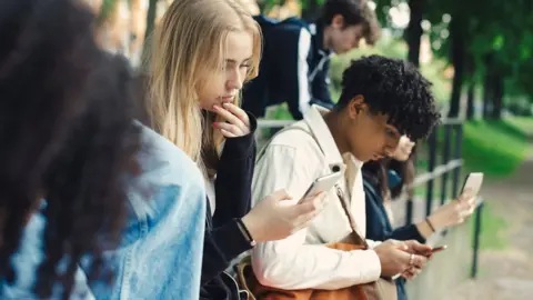 Getty Images Stock photo shows teens outside looking at phones