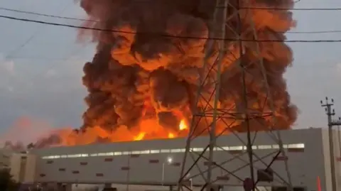 Social Media/Reuters A fire ball rises above a low, light-coloured building. 