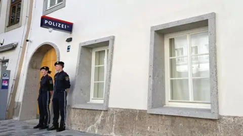 Bethany Bell/BBC Two police officers stand outside a white-washed building with a police sign in German on the wall
