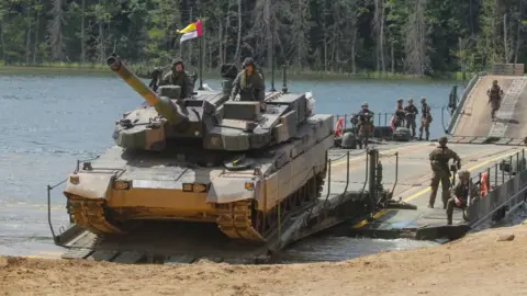 EPA Polish and Lithuanian armed forces in camouflage combat gear are seen conducting tactial water-crossing operations with a tank at a lake in Poland