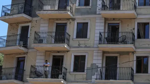 Reuters A resident stands on a balcony of an apartment building damaged by a Russian missile strike, amid Russia's attack on Ukraine, in Odesa, Ukraine July 15, 2026. 