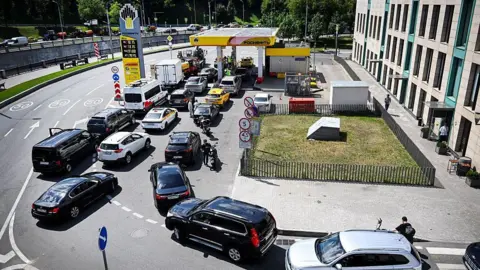 Getty Images People queue to refuel their cars at a Rosneft gas station in Moscow 